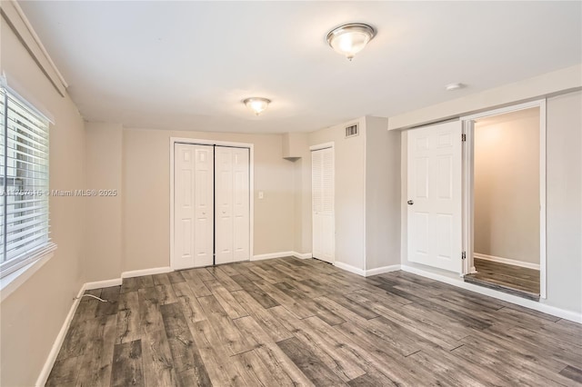 unfurnished bedroom featuring visible vents, baseboards, and wood finished floors