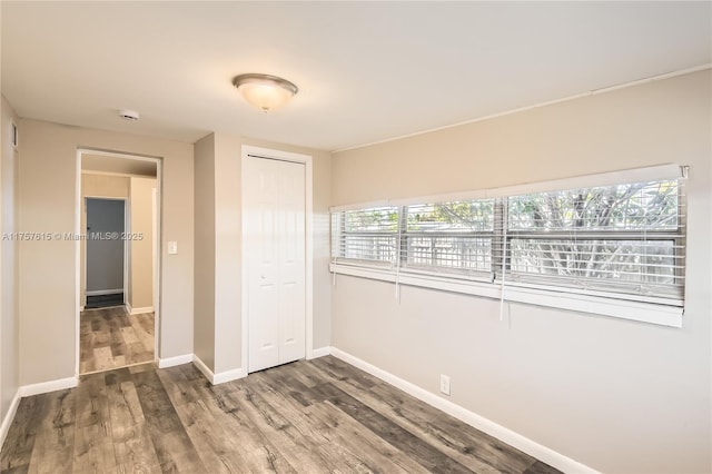 unfurnished bedroom with visible vents, wood finished floors, a closet, and baseboards