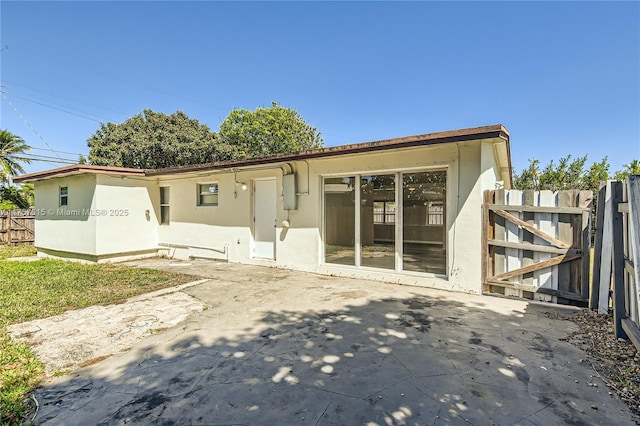 rear view of house featuring stucco siding, a patio, and fence