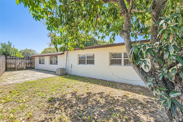 rear view of house with cooling unit, a patio area, fence, and stucco siding