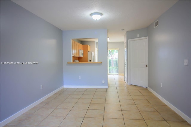 unfurnished room with light tile patterned floors, visible vents, a textured ceiling, and baseboards