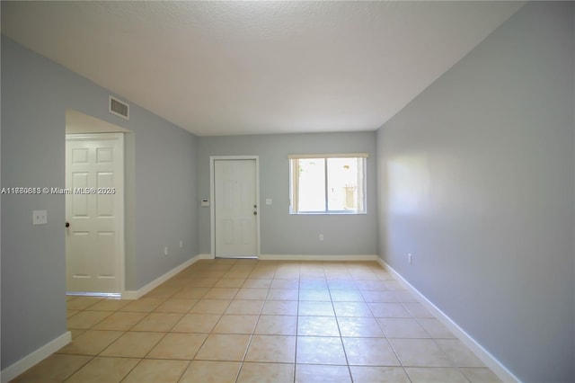 spare room featuring light tile patterned floors, baseboards, and visible vents