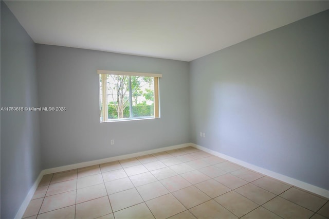 empty room featuring light tile patterned floors and baseboards