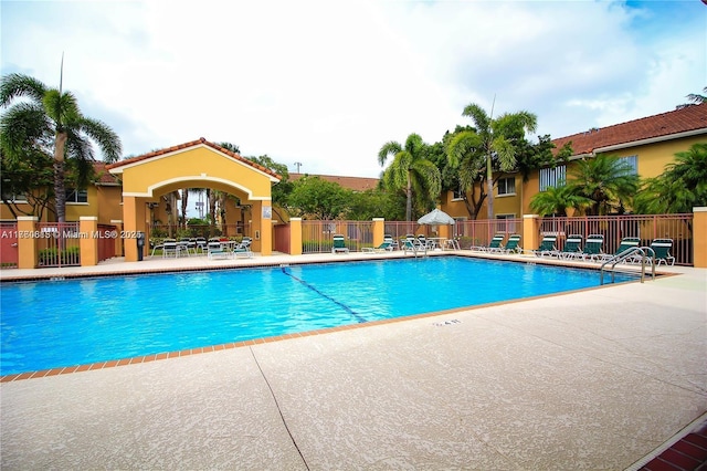 community pool with a patio and fence