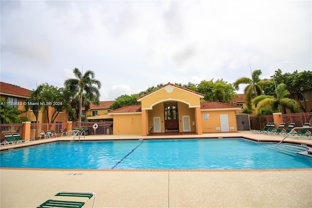 community pool with a patio and fence