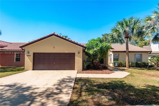 mediterranean / spanish-style home with stucco siding, a front lawn, driveway, an attached garage, and a tiled roof