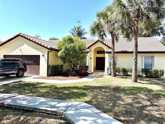 mediterranean / spanish house with stucco siding, a garage, a front yard, and a tile roof