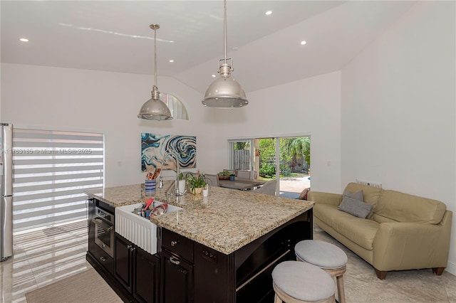 kitchen featuring open floor plan, a breakfast bar, light stone counters, recessed lighting, and appliances with stainless steel finishes