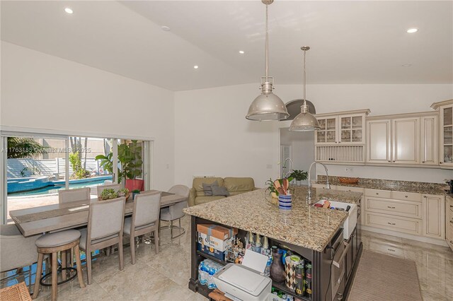 19922 NW 88th Ave, Hialeah, FL 33018 - kitchen with cream cabinetry, a sink, an island with sink, light stone countertops, and glass insert cabinets