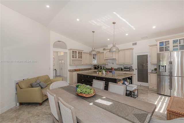 19922 NW 88th Ave, Hialeah, FL 33018 - kitchen featuring stainless steel fridge, cream cabinets, a center island with sink, lofted ceiling, and glass insert cabinets