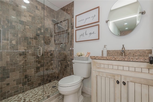 bathroom with a shower stall, toilet, and vanity