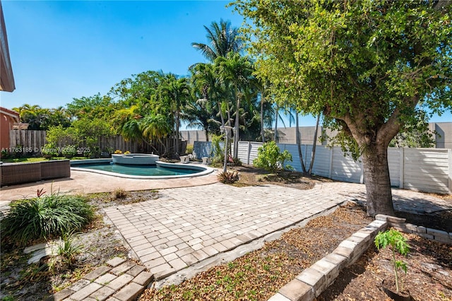 view of patio / terrace featuring a pool with connected hot tub and a fenced backyard