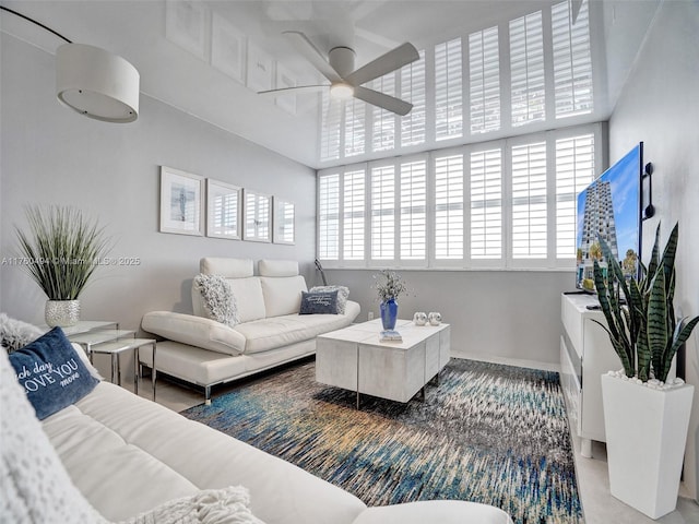 living area with baseboards and ceiling fan