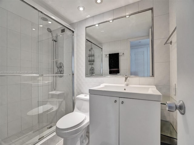 bathroom featuring toilet, a stall shower, tasteful backsplash, tile walls, and vanity