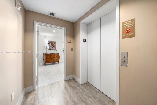 hallway featuring visible vents, elevator, and baseboards