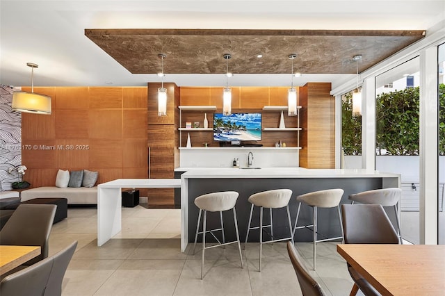 kitchen featuring a breakfast bar area, a sink, light countertops, pendant lighting, and modern cabinets