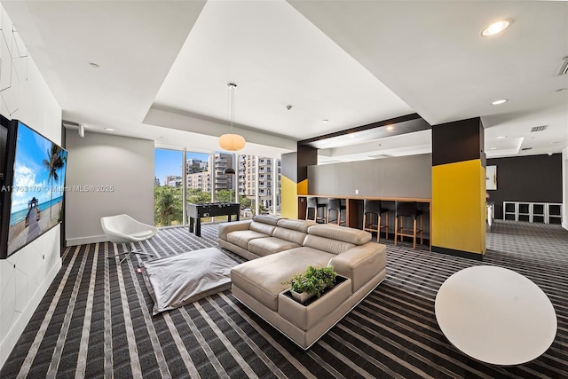 carpeted living room with visible vents, baseboards, a tray ceiling, recessed lighting, and a view of city