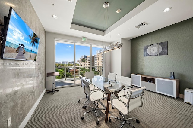 dining area featuring baseboards, visible vents, carpet floors, a tray ceiling, and a city view