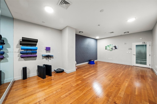 interior space with visible vents, light wood finished floors, wallpapered walls, baseboards, and an accent wall