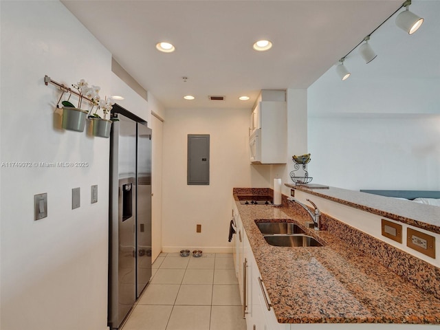 kitchen with a sink, electric panel, white cabinetry, stainless steel fridge with ice dispenser, and light tile patterned floors