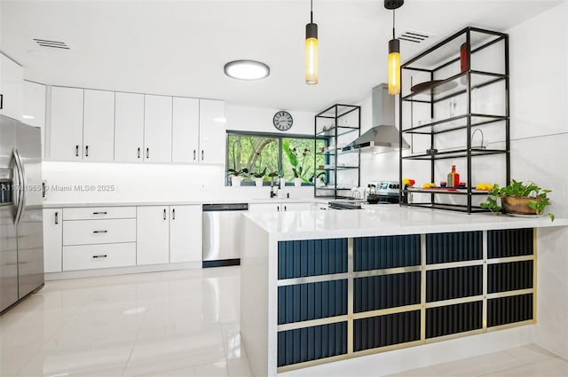 kitchen featuring visible vents, stainless steel appliances, wall chimney exhaust hood, and a sink