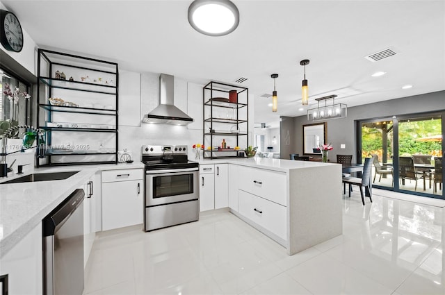 kitchen featuring a sink, white cabinetry, stainless steel appliances, a peninsula, and wall chimney exhaust hood