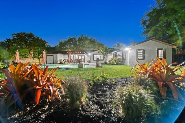 back of property with an outdoor pool, a yard, fence, and stucco siding