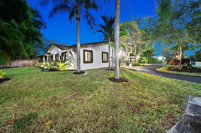 view of side of home with stucco siding, driveway, and a lawn