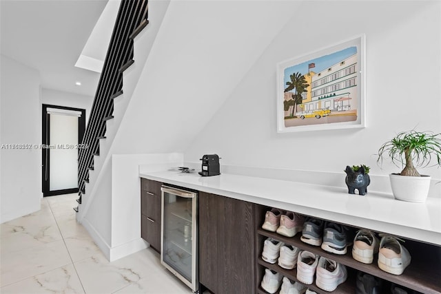 bar featuring baseboards, wine cooler, stairway, marble finish floor, and a bar