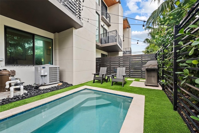 view of swimming pool with central AC unit, a grill, and fence