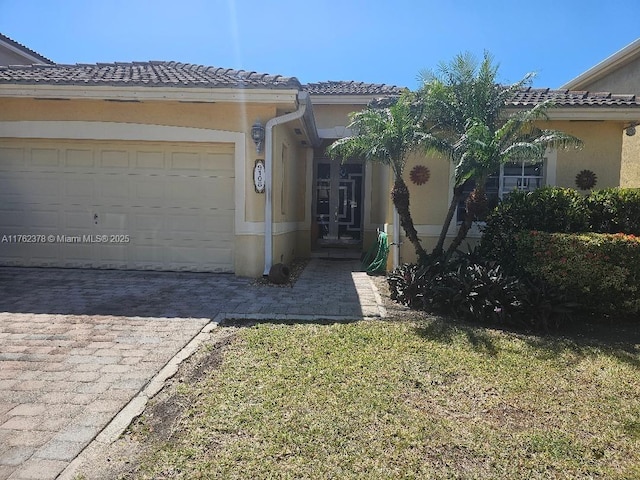 view of front of home with stucco siding, a tiled roof, decorative driveway, and a garage