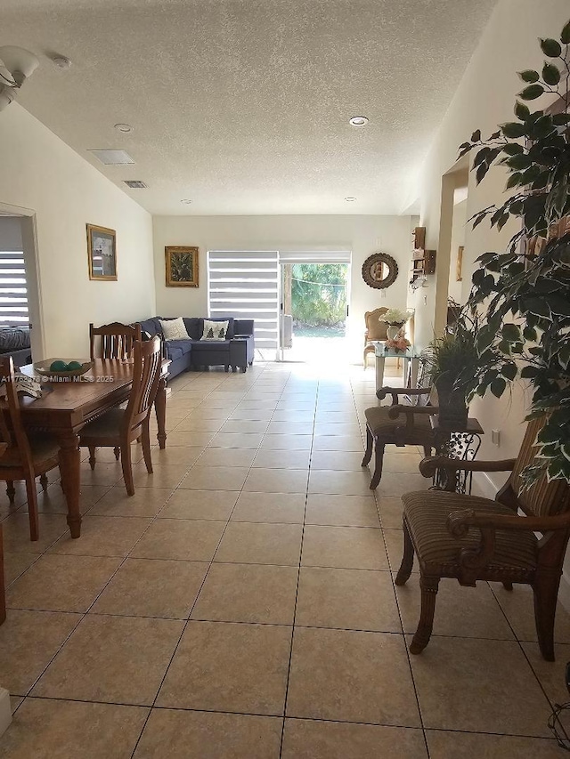 dining space with tile patterned flooring, visible vents, a textured ceiling, and vaulted ceiling