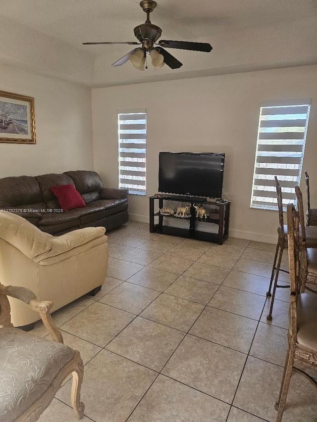 living room with light tile patterned floors, baseboards, and ceiling fan