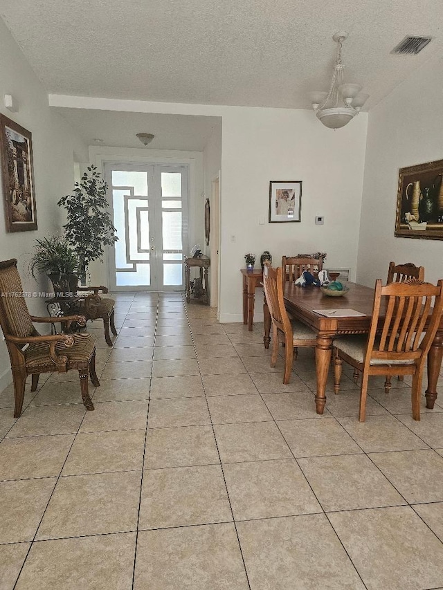 dining space with light tile patterned floors, visible vents, and a textured ceiling