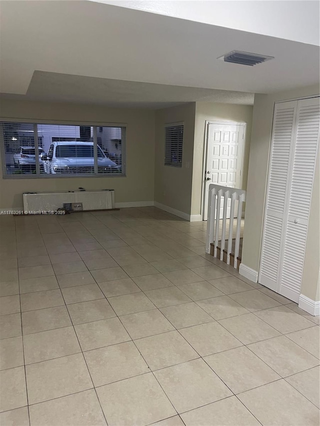 unfurnished living room featuring light tile patterned floors, visible vents, and baseboards