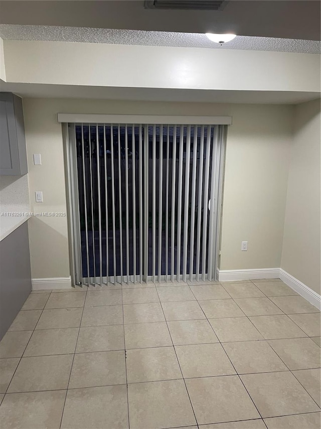 unfurnished room featuring light tile patterned flooring and baseboards