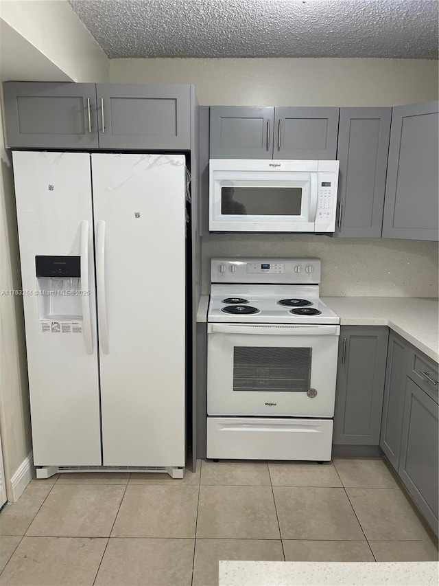 kitchen with white appliances, light tile patterned floors, gray cabinets, light countertops, and a textured ceiling