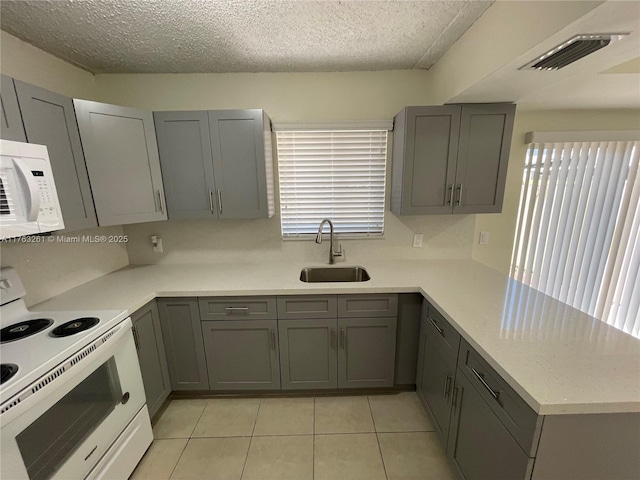 kitchen with white appliances, visible vents, a peninsula, a sink, and light countertops