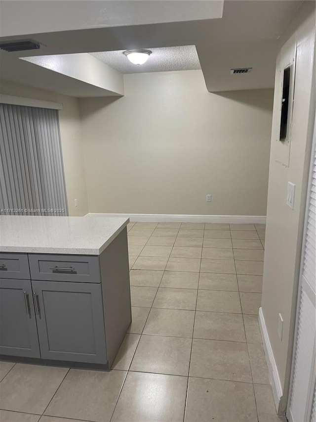 kitchen with light tile patterned flooring, baseboards, and gray cabinetry