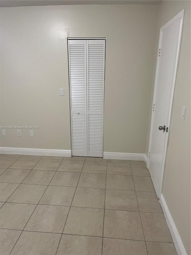 unfurnished bedroom with a closet, baseboards, and light tile patterned flooring