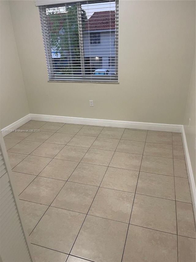 empty room with baseboards and tile patterned flooring