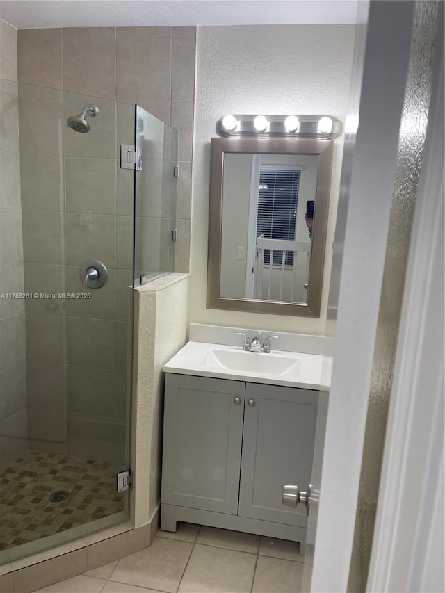 bathroom with tile patterned floors, a stall shower, vanity, and a textured wall