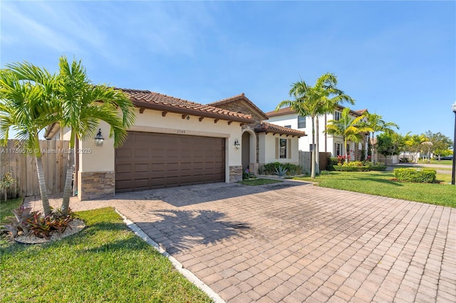 mediterranean / spanish house featuring decorative driveway, stone siding, and stucco siding