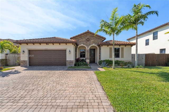 mediterranean / spanish-style house featuring fence, stucco siding, stone siding, a tile roof, and decorative driveway