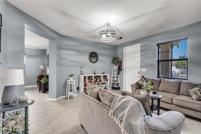 living area with light tile patterned floors, baseboards, a chandelier, and a textured ceiling