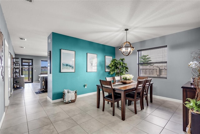 dining area with a notable chandelier, light tile patterned flooring, and baseboards