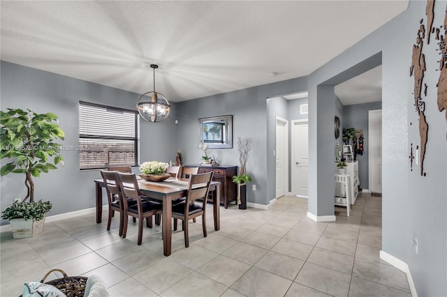 dining space with light tile patterned flooring, a textured ceiling, baseboards, and an inviting chandelier