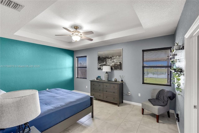 bedroom with visible vents, a raised ceiling, a textured ceiling, and baseboards