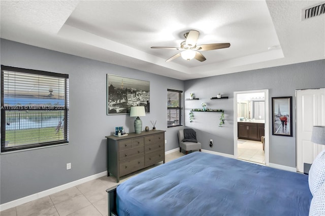 bedroom featuring a raised ceiling, light tile patterned floors, baseboards, and visible vents