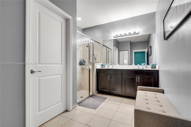 bathroom featuring tile patterned flooring, a shower stall, double vanity, and a sink